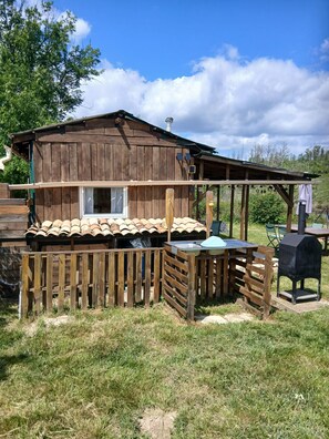 Eine rustikale Holzhütte mit Terrasse, Schornstein und Grill.