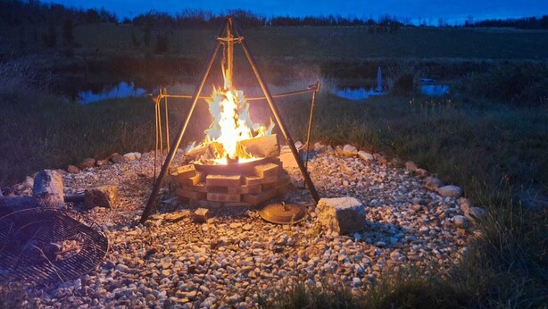 Un fuoco da campo con una griglia in metallo e un braciere in mattoni circondato da rocce.