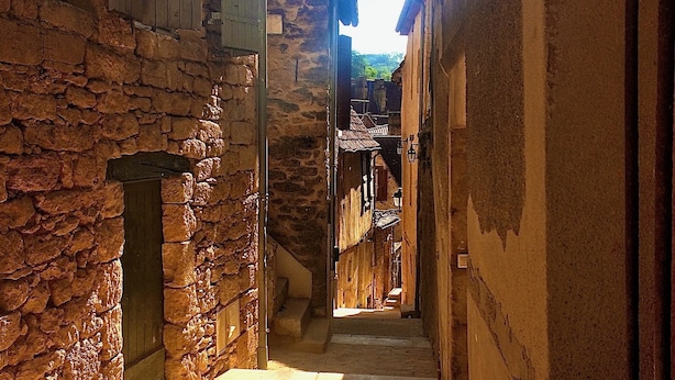 A narrow alleyway with stone walls and wooden doors, leading to a building with a staircase. - Studio in the Medieval Center of Sarlat (FRANREAL) (Sarlat la Caneda)