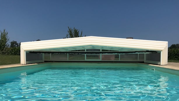 Ein moderner Pool mit klarem, blauem Wasser und einer weißen Dachkonstruktion.