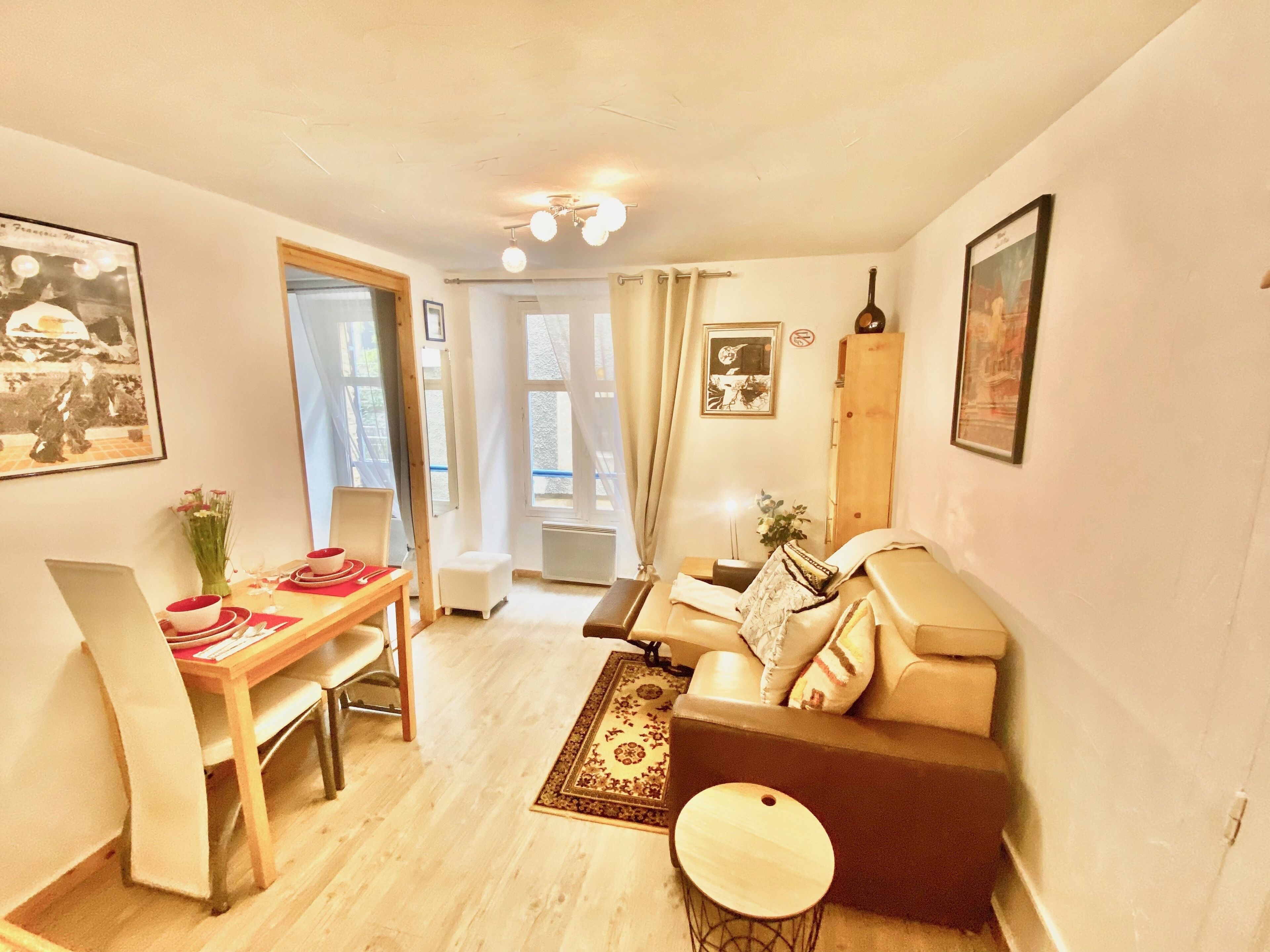 A compact living space with a dining area, a sofa, a small round table, and a radiator.