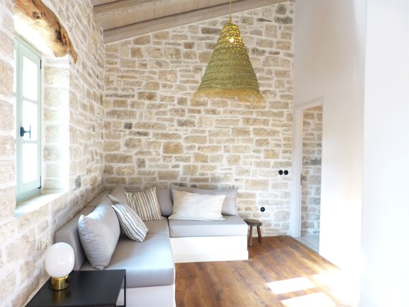 Une pièce avec un mur en pierre, un canapé, une petite table et un luminaire suspendu.