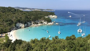 Una zona costera con aguas turquesas cristalinas, embarcaciones y una playa.