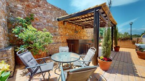 Eine Terrasse im Freien mit Steinmauern, einer Pergola und Sitzgelegenheiten.