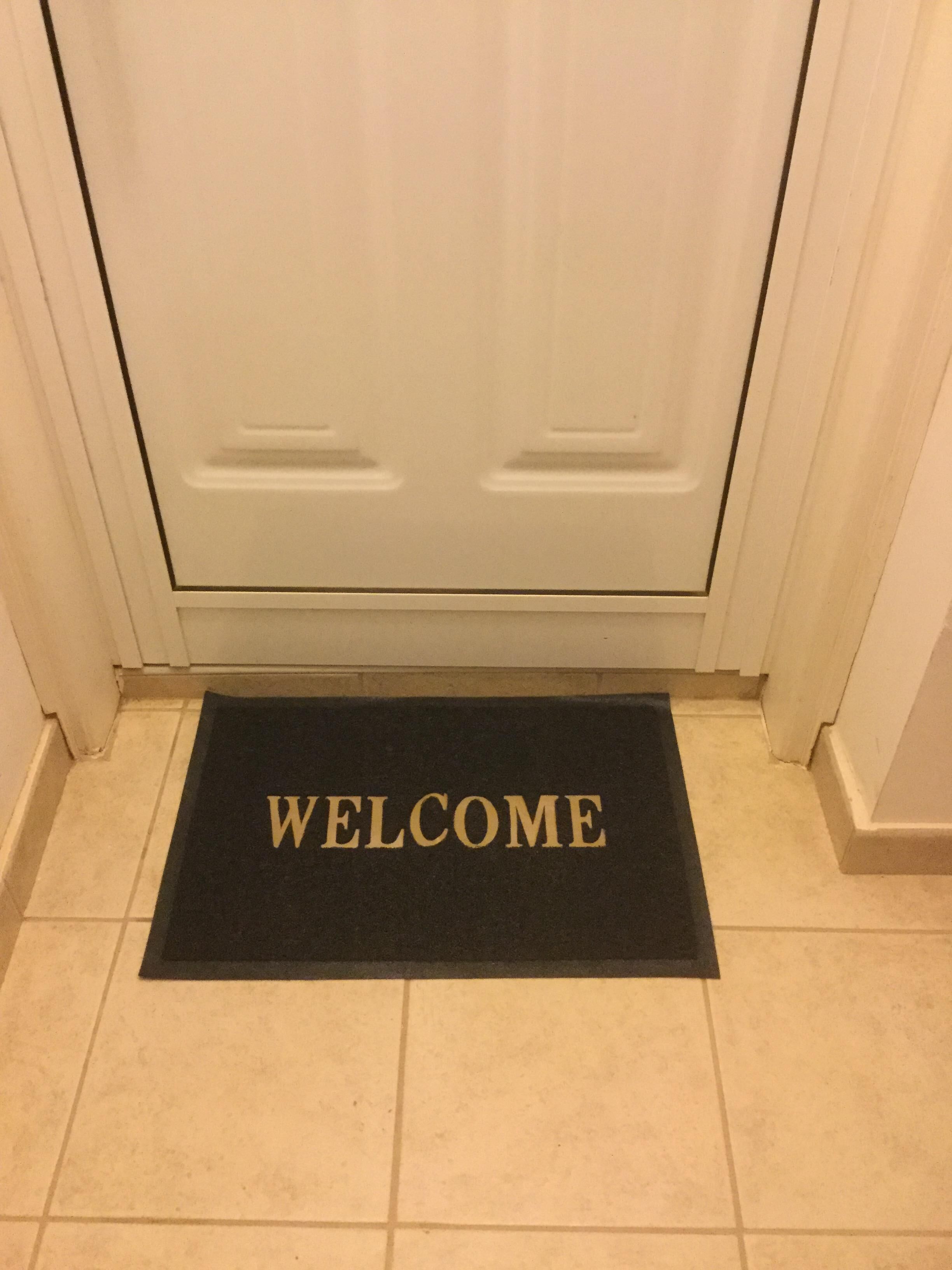 A black welcome mat with the word "WELCOME" in gold letters placed at a door entrance.