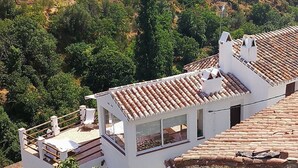 A white building with a tiled roof, a balcony, and a window. - The sky at Salares in Andalusia  (Salares)
