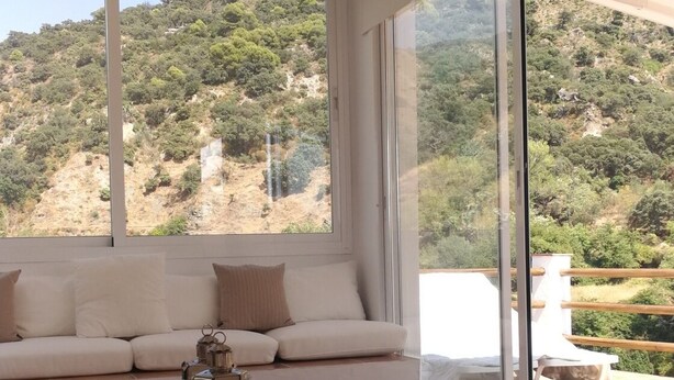 A modern living room with a large window, a sofa, a wooden coffee table, and a view of a mountainous landscape. - The sky at Salares in Andalusia  (Salares)