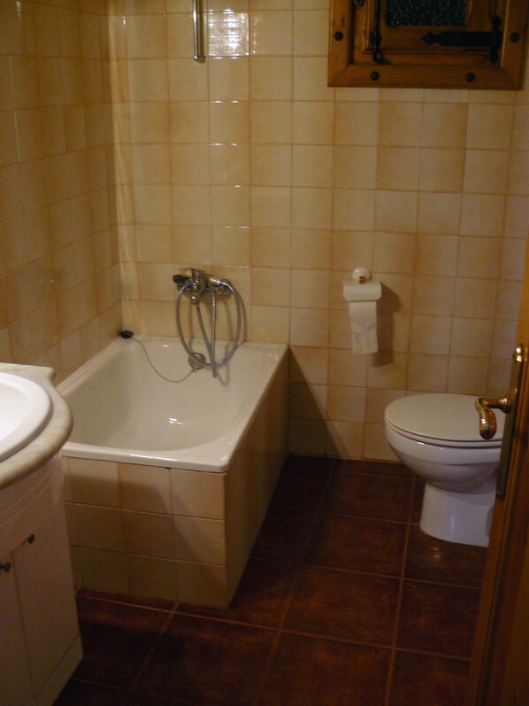 Un baño con bañera, inodoro y lavamanos.