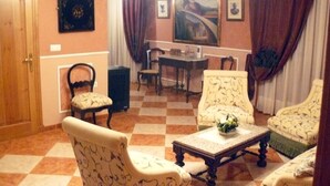 Una habitación con suelo a cuadros, sillones estampados, una mesa de comedor y un cuadro en la pared.