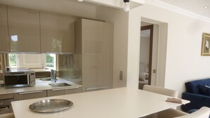 A modern kitchen with a dining area, including a microwave, sink, and stainless steel appliances. - Air-conditioned apartment with large terrace on property with swimming pool (La Roquette-sur-Siagne)