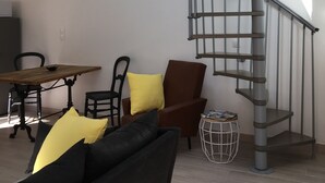 A modern living room with a spiral staircase, a dining area, and a sofa with cushions. - House "Pont Transbordeur" Rochefort city center (Rochefort)