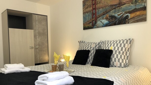 A hotel room with a bed, a painting of the Golden Gate Bridge, and a wardrobe. - House "Pont Transbordeur" Rochefort city center (Rochefort)