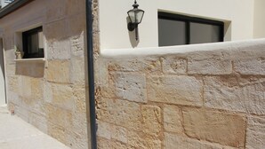 A stone wall with a window and a wall-mounted light fixture. - House "Pont Transbordeur" Rochefort city center (Rochefort)