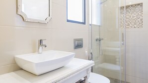A bathroom with a white sink, a mirror, a shower, and a toilet. - Villas Marim Jay Studio One bedroom (Olhão)