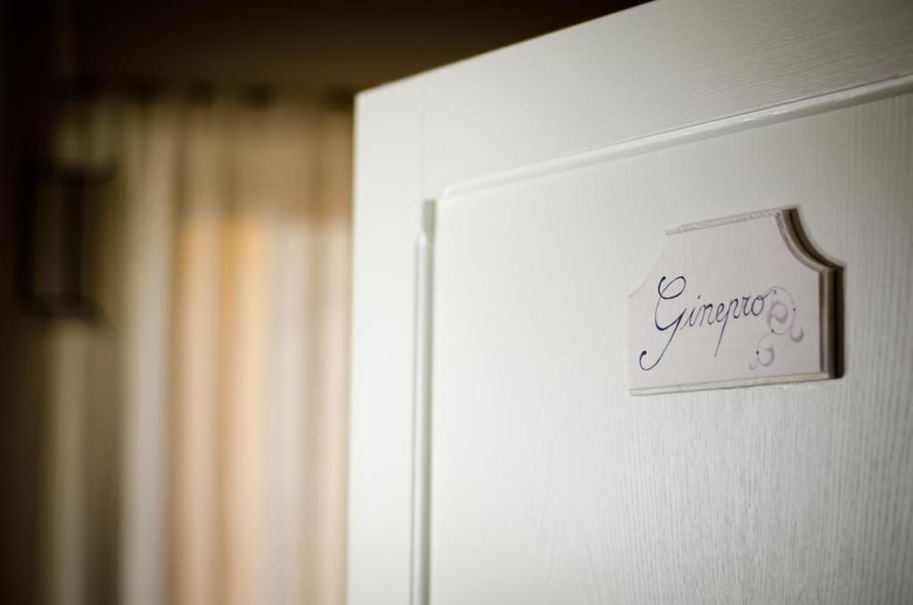 Een detailopname van een deur met een naambordje waarop ‘Ginepro’ staat.