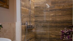 Une salle de bain moderne avec une douche en verre, un lavabo blanc et un sol carrelé en marbre.