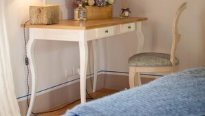 Une chambre à coucher avec un lit, un bureau avec une lampe, une chaise et une affiche accrochée au mur.