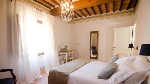 Une chambre à coucher comprenant un lit, un bureau, une chaise, un miroir et un lustre.