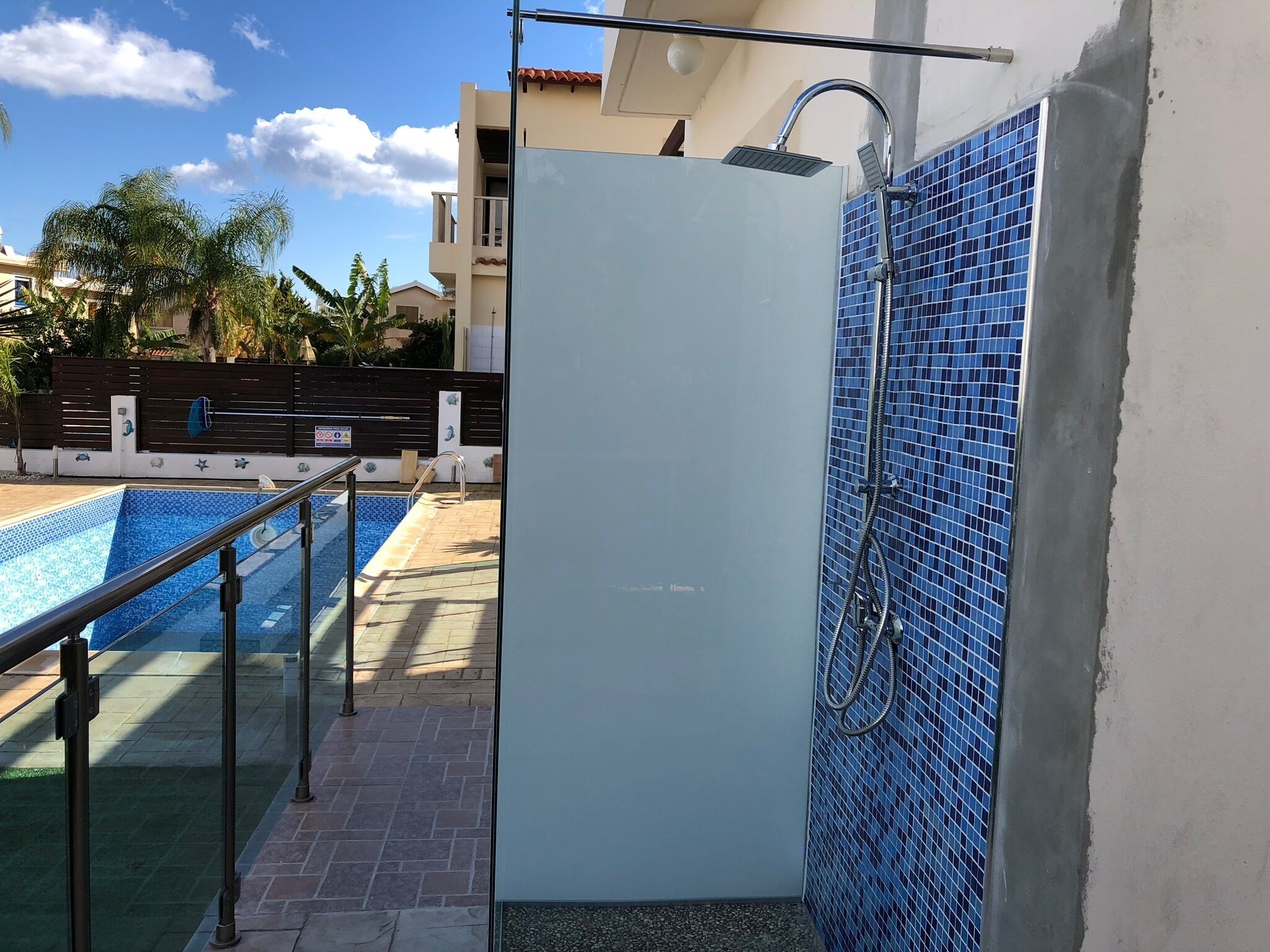 Une salle de bain moderne avec une douche à parois de verre, une piscine et un mur carrelé.