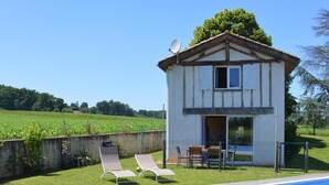 Une piscine avec des chaises longues et un petit bâtiment équipé d’une antenne parabolique.