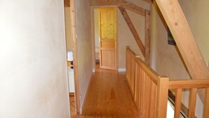 Un escalier en bois mène à une porte dans une pièce aux murs blancs et au plancher en bois.