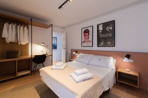 A hotel room with a bed, bedside tables, a desk with a chair, and a wardrobe. - Petit Luxe l'Àtic (Terrassa) (Terrassa)