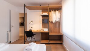 A modern bedroom with a bed, a desk, a chair, a wardrobe, and a radiator. - Petit Luxe l'Àtic (Terrassa) (Terrassa)