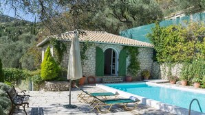 Une villa en pierre dotée d’une piscine, d’un espace extérieur aménagé et d’une végétation luxuriante.