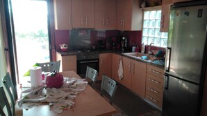 Une cuisine avec des meubles de rangement en bois, un réfrigérateur, une cuisinière et une table à manger avec des chaises.