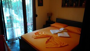Une chambre d’hôtel avec un lit, une literie orange, une table de chevet avec une lampe et une vue par la fenêtre.