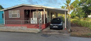 A single-story house with a covered porch, a car parked in front, and a sign indicating a 'Do Not Enter' for the road.