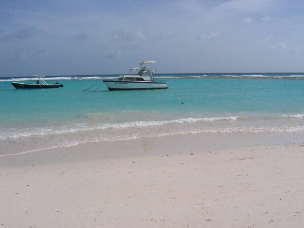 A beach with two boats anchored in the water.