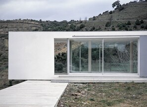 Un edificio moderno con un amplio ventanal y una terraza de hormigón.