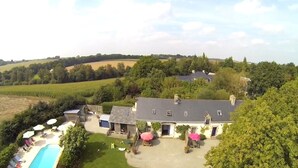 A large house with a swimming pool, surrounded by lush greenery and fields. - House with heated indoor swimming pool  (Évellys)