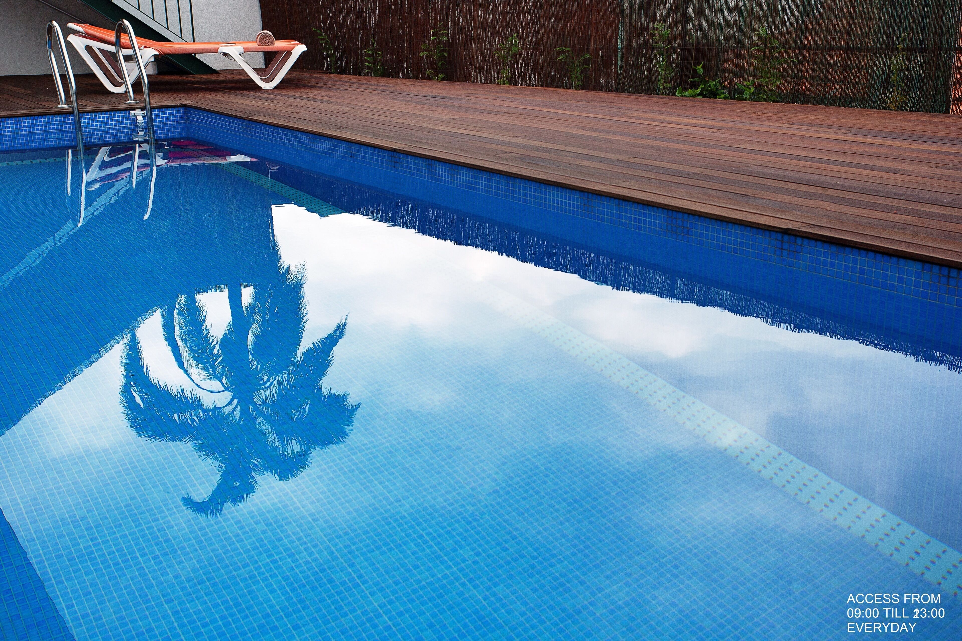 Una piscina con cubierta de madera y escalera metálica.