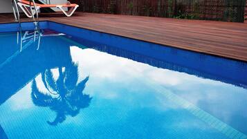 A swimming pool with a wooden deck and metal ladder.