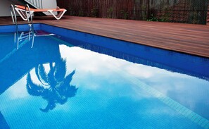A swimming pool with a wooden deck and metal ladder.