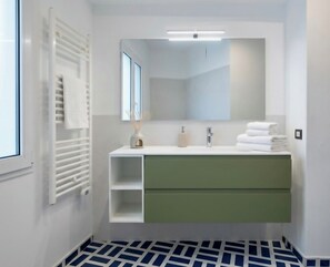 A modern bathroom with a white vanity, a large mirror, and a radiator.
