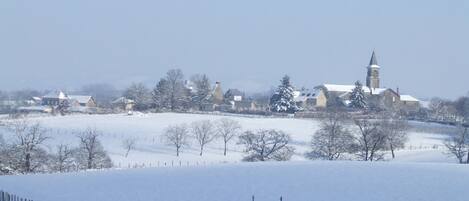 A snow-covered landscape with a church and residential buildings.