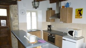 A compact kitchen with wooden cabinets, a built-in oven, a microwave, and a coffee maker. - Farm cottage in activity  (Vaureilles)