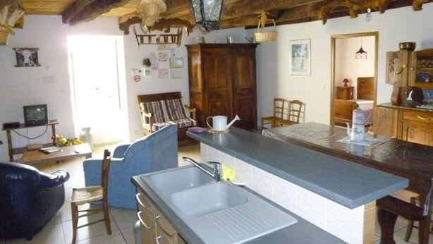 A rustic kitchen with a large island, wooden cabinets, and a hanging light fixture. - Farm cottage in activity  (Vaureilles)