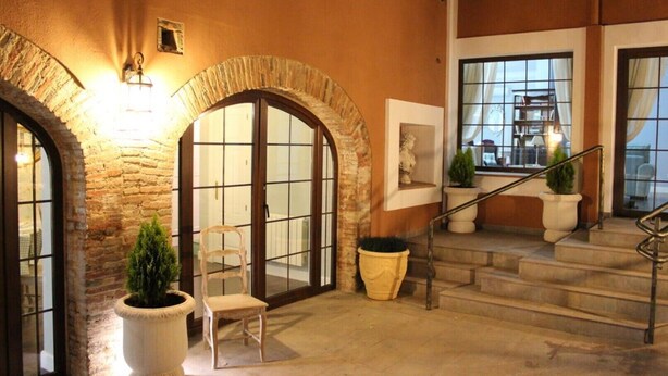 Un vestíbulo de hotel con arcos de piedra, una escalera y una zona de estar.