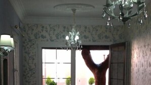 Una habitación con un gran ventanal corredero que da a una zona exterior con mesa, banco y un árbol.