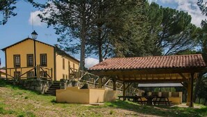 A yellow building with a red-tiled roof, a wooden staircase, and a covered picnic area with benches. - Rural house (full rental) Centro Río Lobos for 6 people (Hontoria del Pinar)