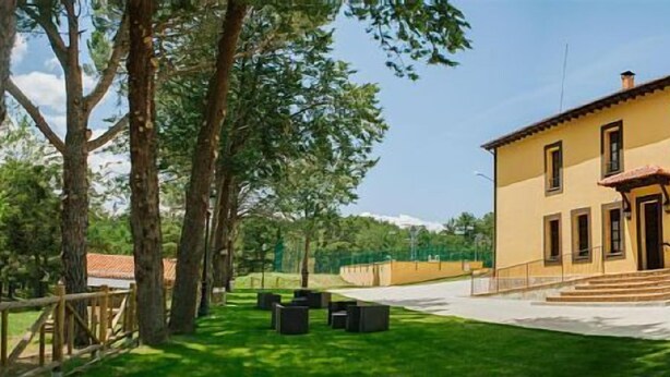 A yellow building with a staircase leading to the entrance, surrounded by trees and a well-maintained lawn. - Rural house (full rental) Centro Río Lobos for 6 people (Hontoria del Pinar)