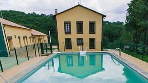 A swimming pool with a view of a yellow building in the background. - Rural house (full rental) Centro Río Lobos for 6 people (Hontoria del Pinar)