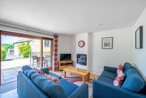 A modern living room with a sofa set, a coffee table, a TV, and a fireplace. - Monmouth Cottage - A peaceful, rural cottage retreat on the outskirts of Frome, near Longleat Safari (Beckington)