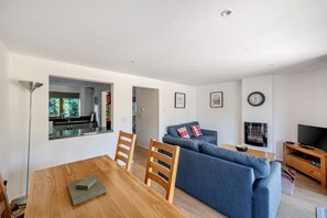 A modern living room with a dining table, sofa, and television. - Monmouth Cottage - A peaceful, rural cottage retreat on the outskirts of Frome, near Longleat Safari (Beckington)