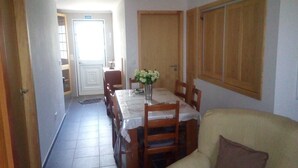 A dining area with a table set for four, a vase with flowers, and wooden chairs. - Calm and rest combined with well-being with great views of the mountain and sea (Madalena)