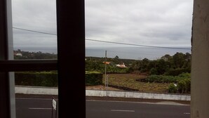 A view through a window of a road with a signpost, greenery, and distant buildings. - Calm and rest combined with well-being with great views of the mountain and sea (Madalena)